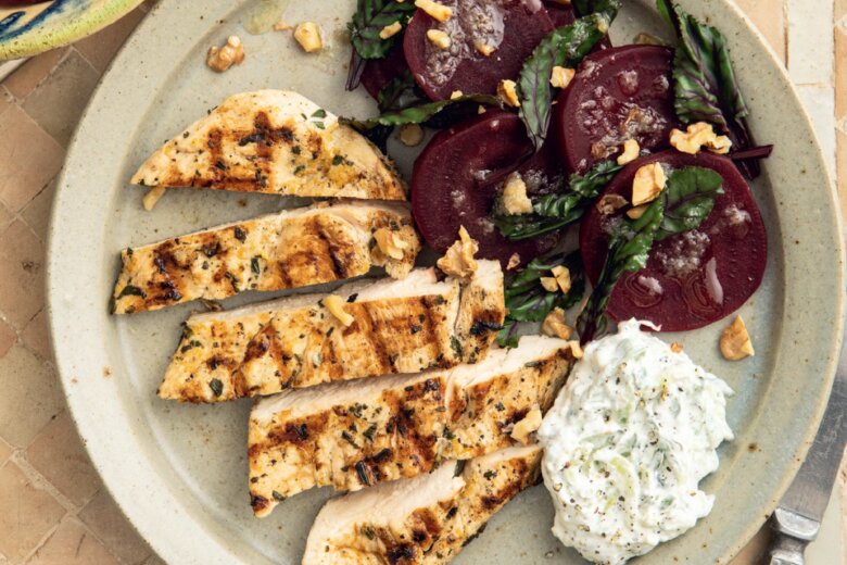 A plate with the Hairy Dieters' grilled chicken breast slices, a side of beet salad with chopped herbs, and a serving of tzatziki sauce.
