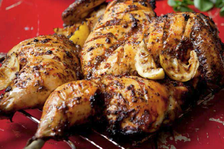 Grilled, seasoned Piri Piri Chicken with lemon slices on a wire rack, garnished with watercress – straight out of Hairy Dieters 'Eat for Life' cookery book