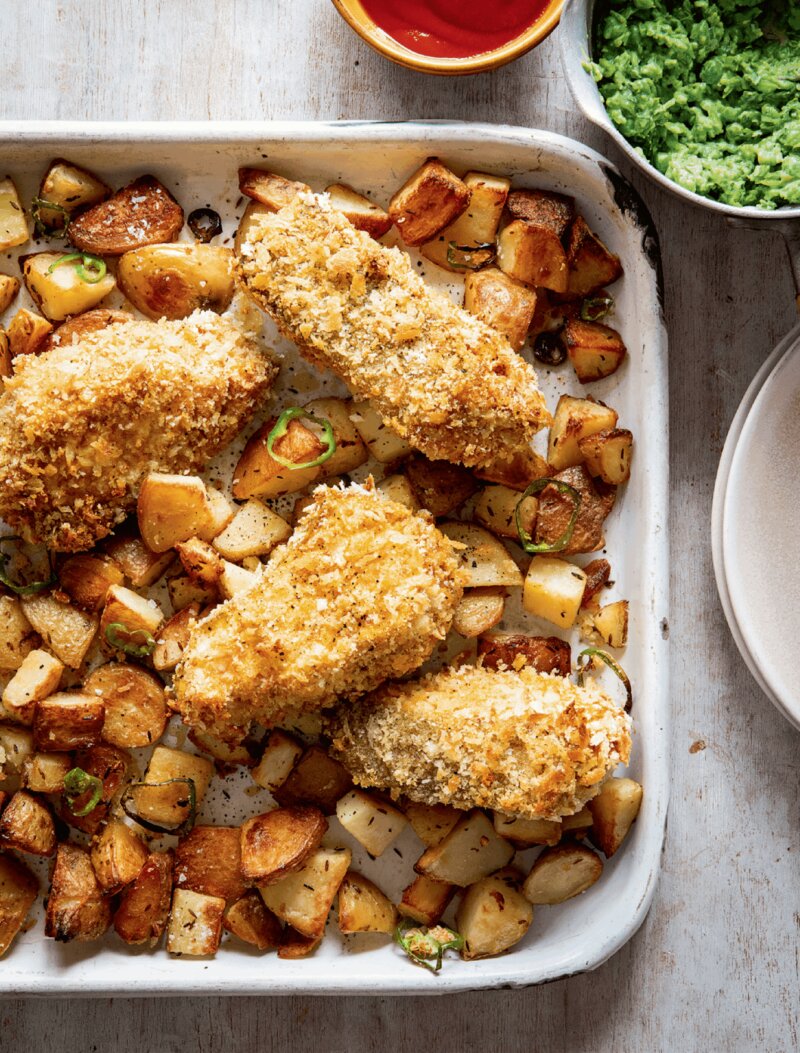 A baking tray with breaded fish on a bed of fried diced potatoes, from the Hairy Bikers Everyday Winners cookery book.