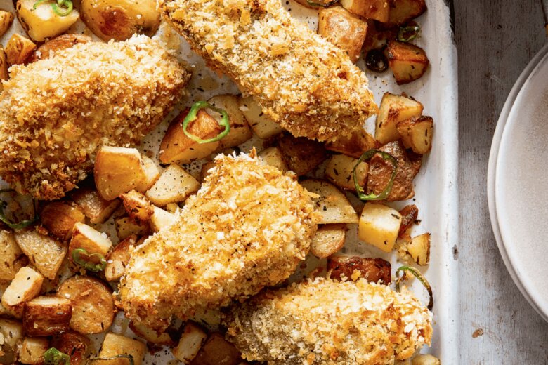 A baking tray with breaded fish on a bed of fried diced potatoes, from the Hairy Bikers Everyday Winners cookery book.
